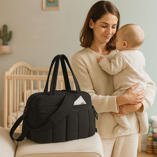 une maman avec son bebe et le sac a langer noir
